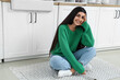 © Pixel-Shot - Pretty young woman sitting on rug in light kitchen