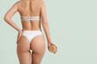 © Pixel-Shot - Young woman with massage brush and scrub on butt against light background
