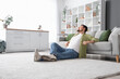 © Pixel-Shot - Young man sitting on soft carpet at home