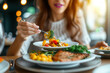 © KirKam - A woman enjoys a nutritious meal at a restaurant, savoring a deliciously prepared salmon dish with fresh vegetables.