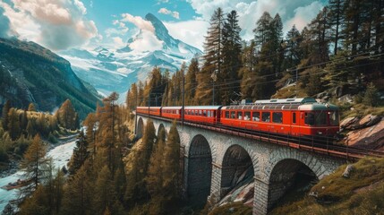 Wall Mural - A red train is traveling over a bridge in the mountains