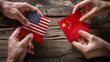 © ARM - Two hands exchanging envelopes, one featuring the American flag and the other the Chinese flag, on a wooden table