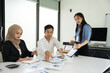 © Thitisak - Group of Asian business people planning a project, discussing work documents.