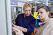 © auremar - senior female worker training new recruit to use machine
