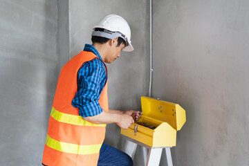 Wall Mural - Asian worker opening tool boxes in construction site.