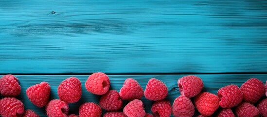 Wall Mural - Close up copy space image of raspberries arranged on a vibrant blue wooden table