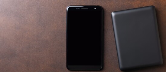 Fototapete - Top view of a Black smart phone and a black power bank being charged on a paper background with copy space image available