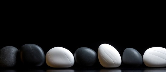 Smooth white sea stones on a dark wooden surface set against a striped black background Ample copy space for adding text to the image