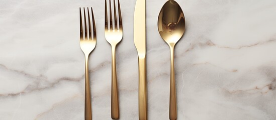 Poster - Design concept with clean golden metal cutlery on a light marble background in a top view copy space image