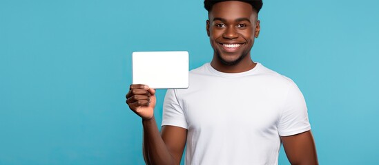 Poster - A young African man presenting a digital tablet with a blank screen against a blue backdrop suitable for a copy space image