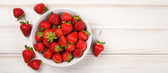 Poster - Top view copy space image of a white wooden background with a heap of fresh strawberries in a bowl