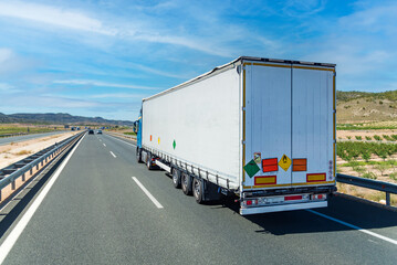 Wall Mural - Large tonnage truck traveling on a highway with license plates and labels for dangerous goods, non-flammable gases under pressure and oxidizing material. Category 5.1 in ADR.