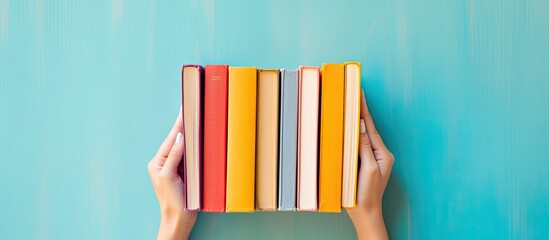 Poster - Female hands holding books on a colorful background creating a visually appealing copy space image