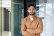 © Tetiana - Confident young man with glasses standing and smiling in a modern office environment