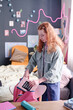 © AnnaStills - Red-haired girl standing in her room packing her backpack before going to school, vertical medium long shot
