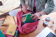 © AnnaStills - High angle view of unrecognizable student getting ready for school packing her backpack, copy space