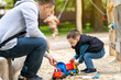 © Andrii Yalanskyi - Little cute toddler boy three years old with dad plays in the sandbox on a spring day. Outdoor development activities for kids. Family spending time. Toy cars