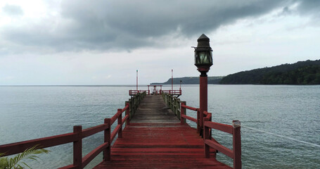 Wall Mural - an ocean dock with a lamp on the wooden pier and mountains behind. Bom bom beach, Africa