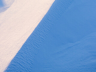 Wall Mural - Snow texture. Wind sculpted patterns on snow surface. Wind in the tundra and in the mountains on the surface of the snow sculpts patterns and ridges (sastrugi). Arctic, Polar region. Winter background