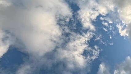 Wall Mural - Time-lapse low angle of the white clouds floating in the blue sky on a sunny day