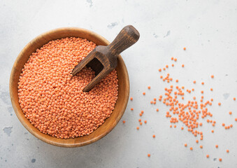 Wall Mural - Dry raw orange lentils seeds in wooden bowl with scoop on light table.Macro.