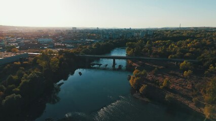 Wall Mural - Drone footage of a bridge crossing the Maritsa River in Dimitrovgrad town at sunset, Bulgaria