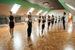 © standret - Standing together. Group of female kids practicing athletic exercises indoors
