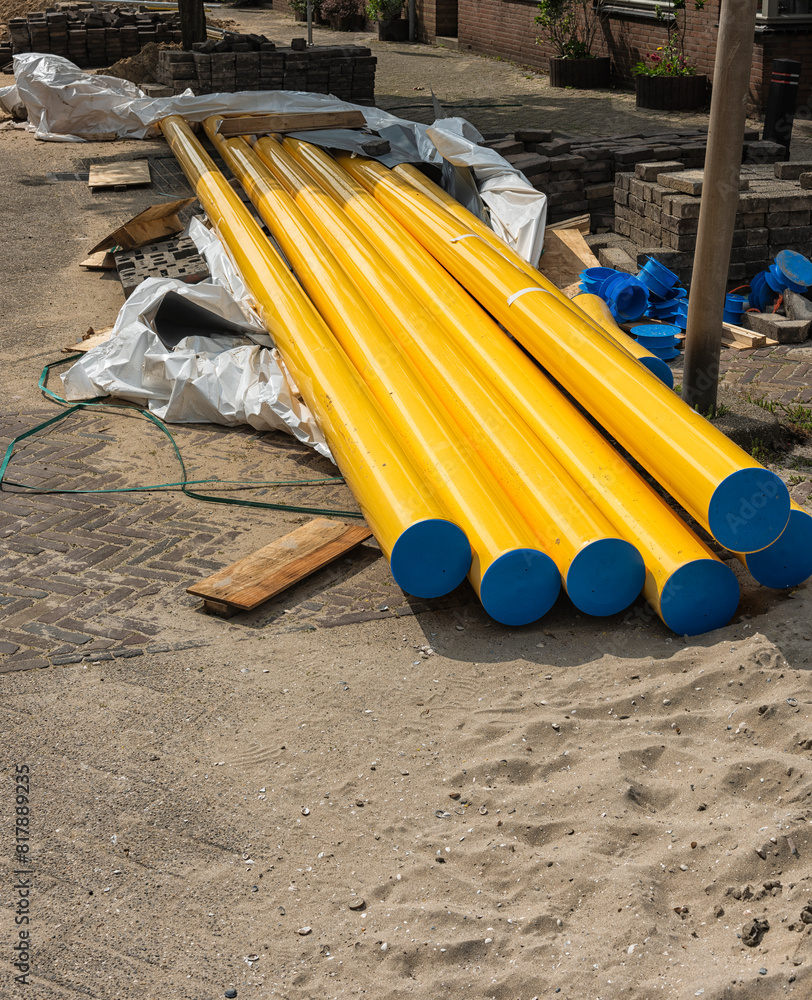 yellow plastic gas pipes with a blue cap lie outside on the sand