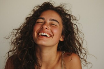 Joyful Young Woman with Curly Hair Laughing Heartily in Studio