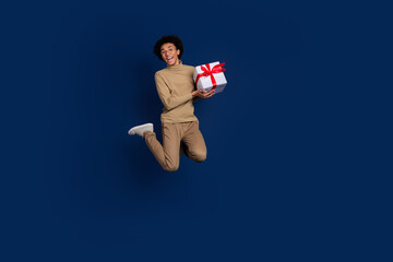 Sticker - Full body photo of attractive young man jump hold present dressed stylish beige clothes isolated on dark blue color background