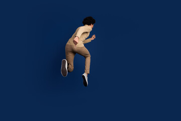 Poster - Full size photo of nice young man running back view wear trendy beige outfit isolated on dark blue color background