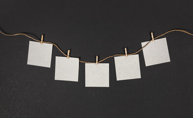 Wall Mural - clothespin hanging with blank paper on dark background