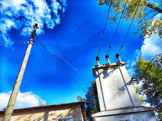 Sunlit Electrical Transformer on a Clear Day. Sunny day showcasing a transformer with power lines against a blue sky