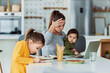 © Jelena - A stressed single mother working from home on a laptop and looking after her children