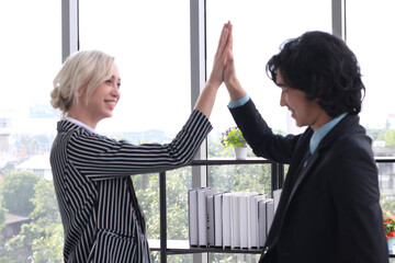 Successful yong businessman and businesswomen high five together, feeling good from well done work with  project complete, solf focus, blur background