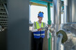 © ultramansk - Male engineer monitoring machinery on a rooftop with city skyline in the background, wearing safety gear