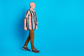 Sticker - Full length photo of smiling sucessful retired man wear striped trendy clothes walk empty space isolated on blue color background