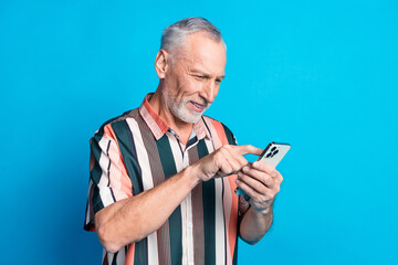 photo of cheerful nice senior man wear striped trendy clothes use device write post isolated on blue