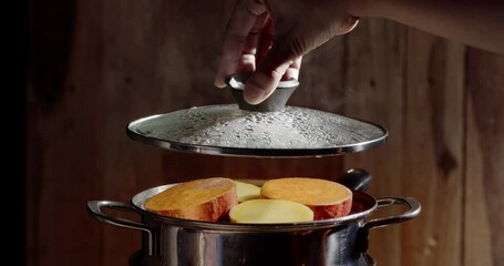 Wall Mural - Slow motion of steamed sweet potatoes in boiling pot steams up as a chef opens the lid of a pot.