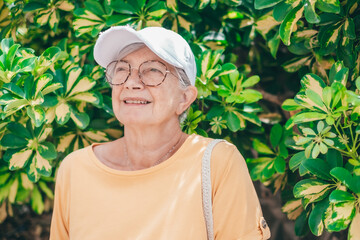 Sticker - Portrait of senior smiling woman in yellow sitting in the park looking awat. Elderly lady relaxing enjoying free time in nature