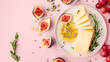 © Нина Башарова - Cheese plate, honey, figs, grapes and rosemary on an isolated light pink background, top view.