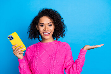 Poster - Photo of nice young girl hold smsart phone empty space wear pink sweater isolated on blue color background