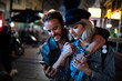 © Marko Geber - Couple hugging and laughing while looking at smartphone on city street at night