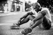 © Geber86 - Black and white photo of active man sitting on street after workout outdoors