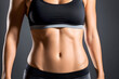 © Ocharonata - female flat athletic belly with abs in black sportswear on dark background