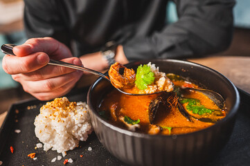 Poster - man eating thai tom yum soup in a restaurant