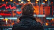 © K-MookPan - A young man stands in front of a large screen displaying stock market data