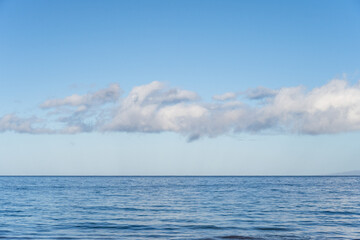 peaceful, serene, and calming blue nature background of flat pacific ocean reaching to a blue sky ho
