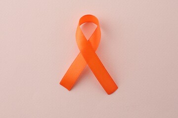 Wall Mural - Orange awareness ribbon on beige background, top view