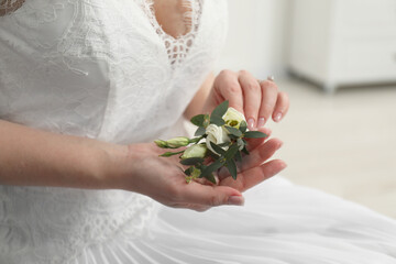 Wall Mural - Bride holding boutonniere for her groom on blurred background, closeup